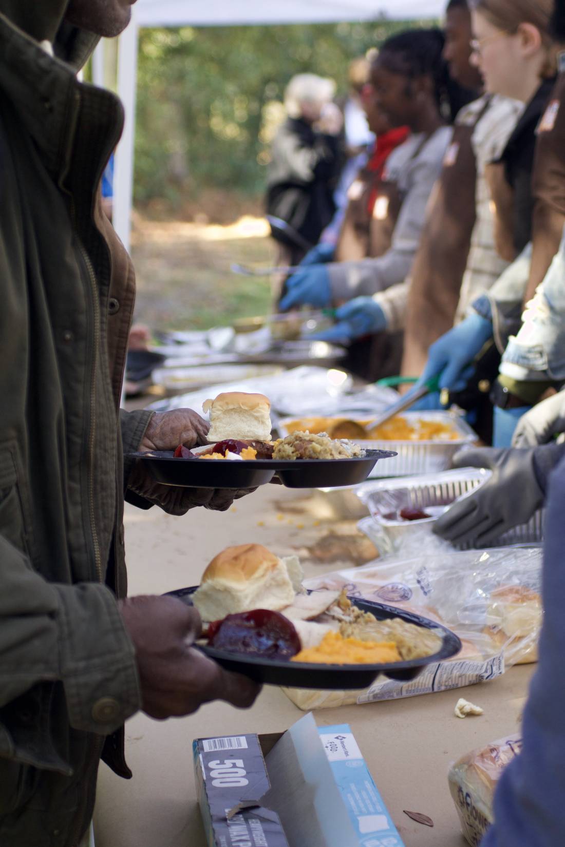 A plate of smoked turkey, dressing, cranberry sauce and a roll, held at the serving line.